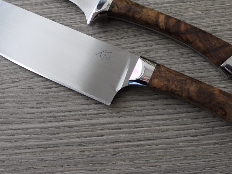 Forged chef's knife with burl wood handle on a wood-grain surface
