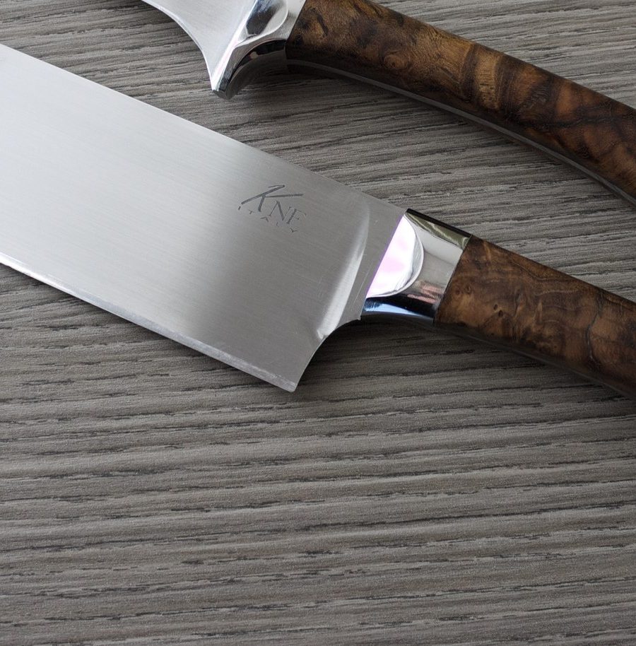 Forged chef's knife with burl wood handle on a wood-grain surface