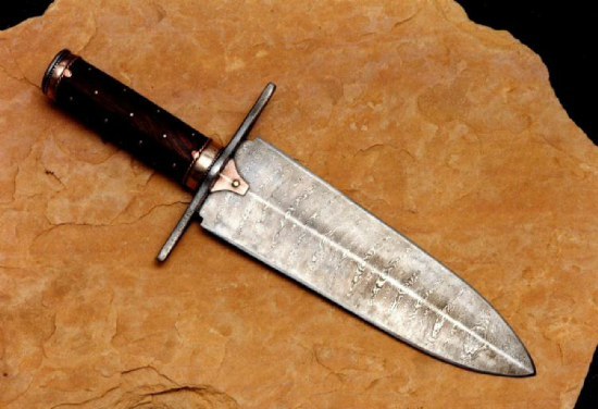 Damascus steel dagger with wood and brass handle on stone