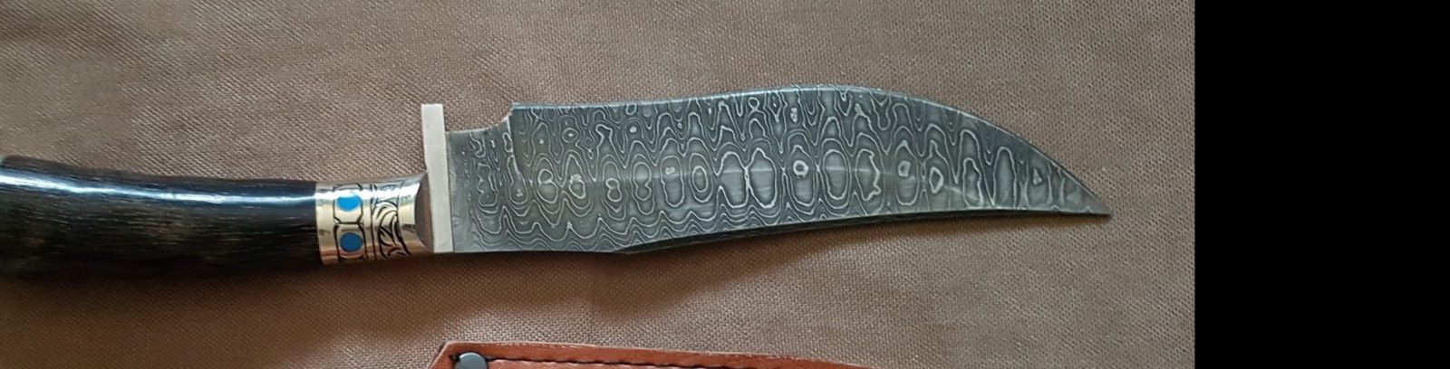 Curved dagger blade showing a dense mosaic Damascus pattern