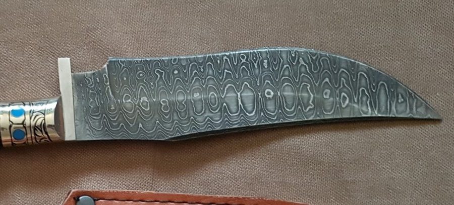 Curved dagger blade showing a dense mosaic Damascus pattern