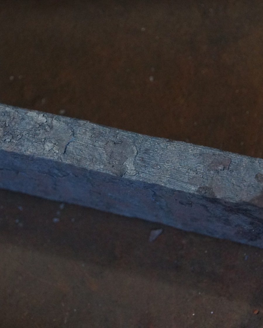 Close-up of a forged plain carbon steel bar with oxide finish