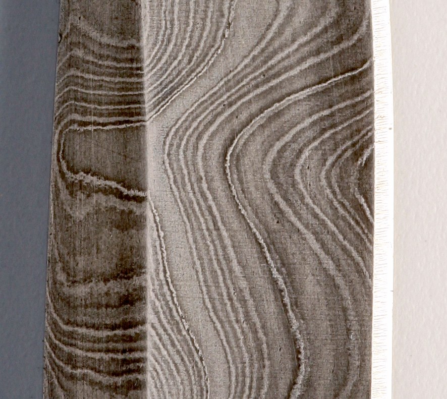 Close-up of ladder-pattern Damascus steel showing layered grain