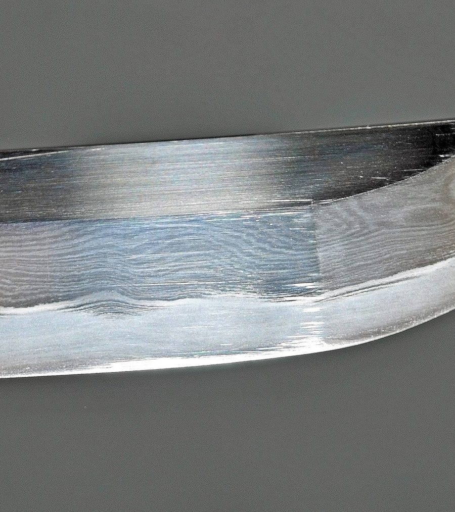 Polished carbon steel blade tip showing a visible hamon temper line